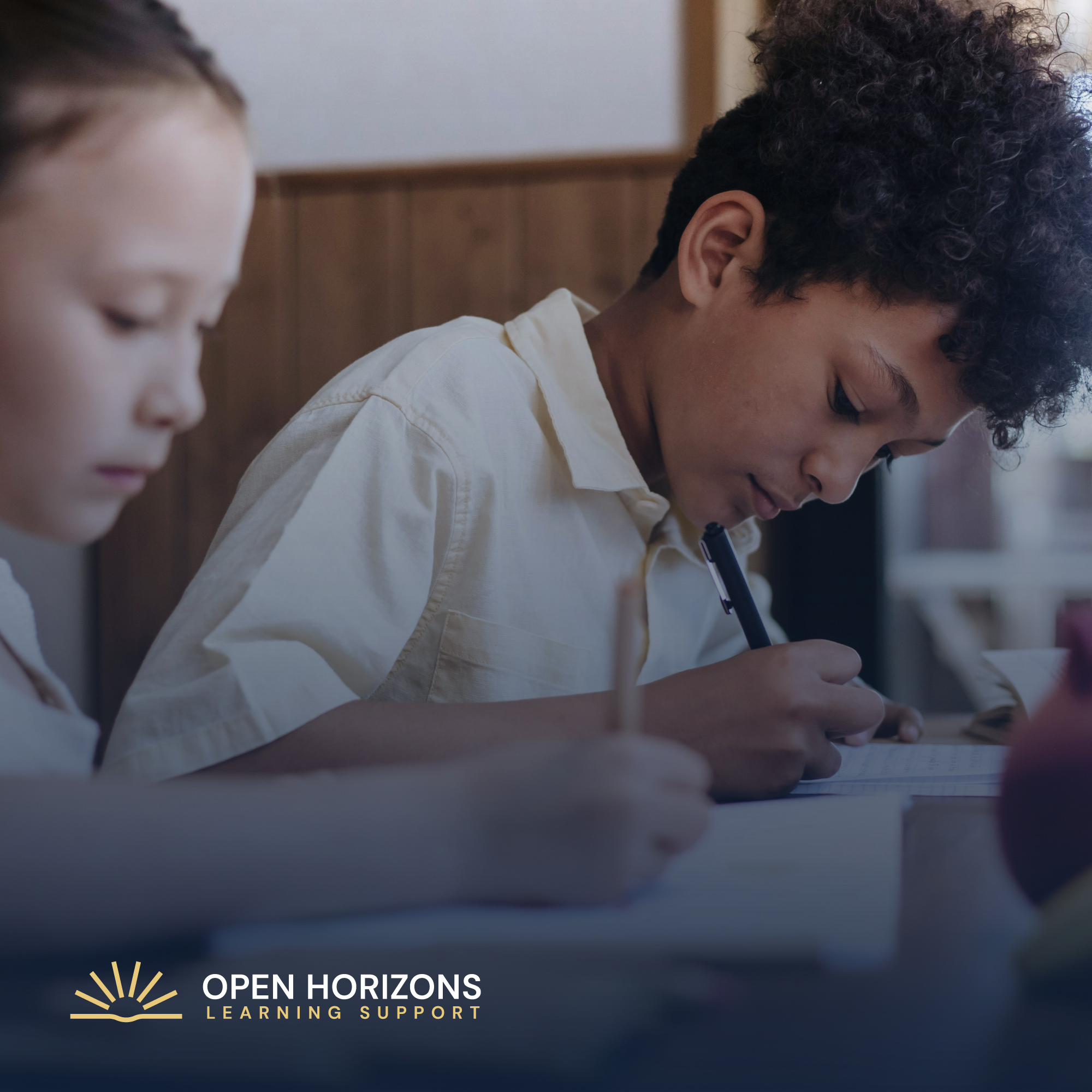 Children writing at a classroom desk, with the Open Horizons Learning Support logo overlaid